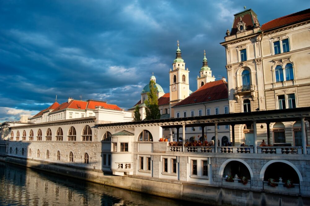 Plečnik's arched Central Market colonnade reflecting in the Ljubljanica River in Ljubljana, Slovenia